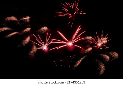 Bright Festive Fireworks Against  Black Night Sky. Flashes And Colorful Rays Of Light In Dark.