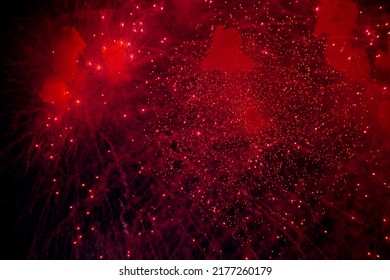 A bright firework with a red glowing center with red sparks and smoke flying towards the background of the night sky. High quality photo