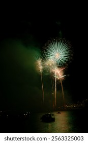 Bright fireworks exploding over boats on the water illuminating the night sky