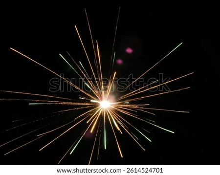 Bright fireworks explosion with orange and green streaks radiating from the center,captured in high detail with long exposure at night