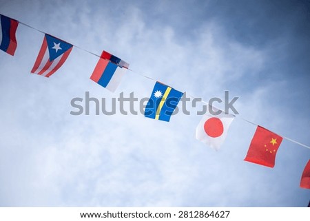Bright flags representing different nations are strung across the sky, creating a colorful and lively display that symbolizes unity, diversity, and celebration.