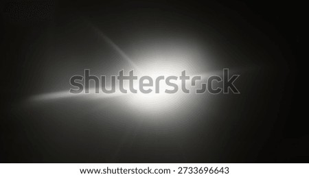 A bright flash of light creating a glare on a dark background, evoking a sense of mystery. Real optical lens flare on a black background, star glare.