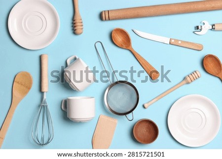 Bright flat lay of assorted kitchen utensils and cookware arranged on a blue background giving a fresh cooking vibe