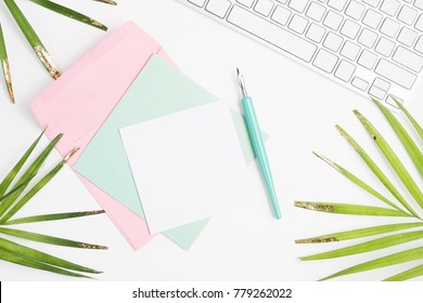 Bright flat lay fashion mock up: white keyboard, golden palm leaves, colorful cards, envelope and dip pen on white background. Text space