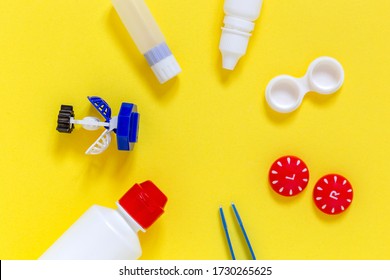 Bright flat lay of vision correction lenses equipment on yellow background with copy space : eye drops, containers, lenses, twizzlers