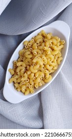 Bright Flatlay Photo Of Elbow Macaroni In White Oval Plate On Gray Background 