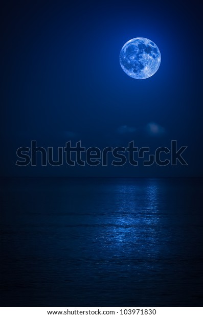 Bright full moon with reflections on a calm\
ocean at midnight