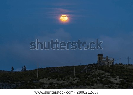 Bright full moon shining through thin clouds in a deep blue evening sky. Atmospheric night sky scene with detailed lunar surface, soft cloud formations, and a tranquil celestial landscape ideal for astronomy, nature, and background concepts.