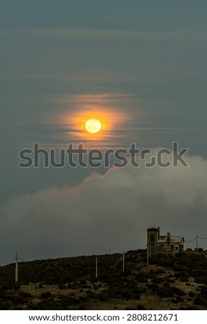 Bright full moon shining through thin clouds in a deep blue evening sky. Atmospheric night sky scene with detailed lunar surface, soft cloud formations, and a tranquil celestial landscape ideal for astronomy, nature, and background concepts.