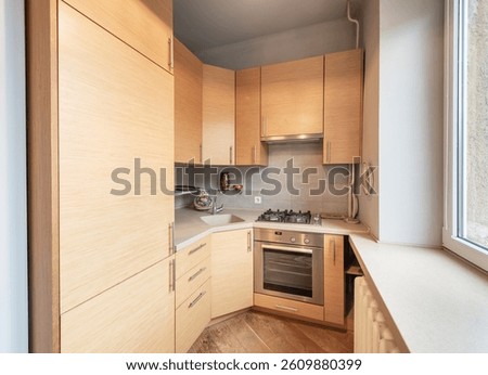 Bright and functional small kitchen featuring modern light wooden cabinets, integrated appliances, and tiled backsplash. A space-efficient design showcasing warmth and practicality