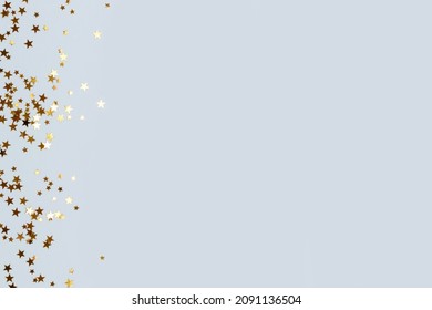 Bright Gold Glittering Stars Confetti Scattered On A Blue Pastel Background With Place For Text.