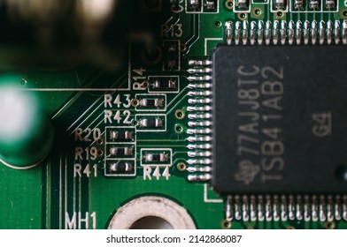 Bright green microchip processor board from a computer showing connections electronics soldering batteries and other components