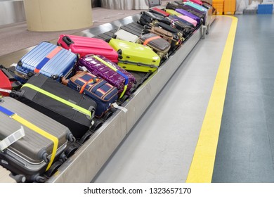 Bright green, pink and blue suitcases on luggage conveyor belt at arrival area of passenger terminal in airport. View of baggage carousel. - Shutterstock ID 1323657170