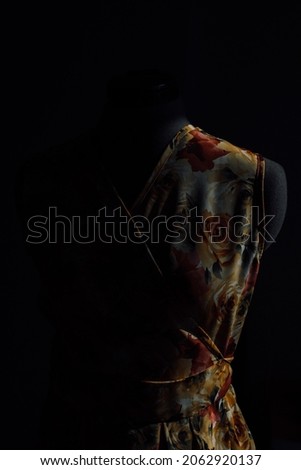 a bright handmade summer dress on a mannequin. a fashion designer makes a sundress of individual tailoring. fabric with a pattern of flowers. photo of clothes on a mannequin on a dark background