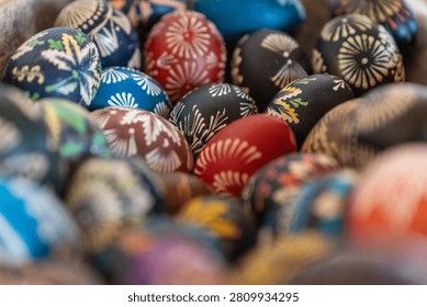 Bright, hand-painted Easter eggs (pysanky) with intricate folk patterns nestle in a rustic bowl, conveying tradition, spring celebration, craftsmanship and vibrant seasonal color.