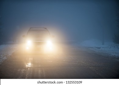 Bright Headlights Of A Car Driving On Foggy Winter Road