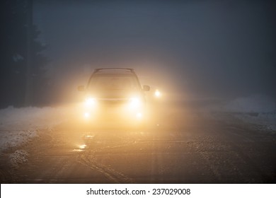 Bright Headlights Of A Car Driving On Foggy Winter Road