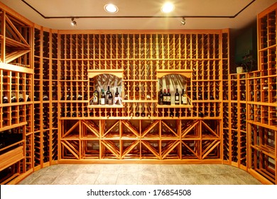 Bright home wine cellar with wooden storage units and arch with bottles.