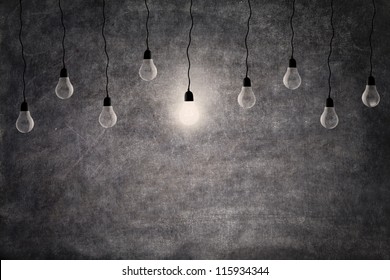 Bright idea concept: on and off light bulbs in front of empty blackboard with copy space - Powered by Shutterstock