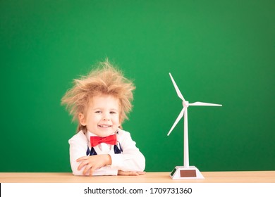 Bright Idea! Funny Child Student With Wind Turbine. Happy Kid Against Green Chalkboard. Alternative Wind Energy Concept. Back To School