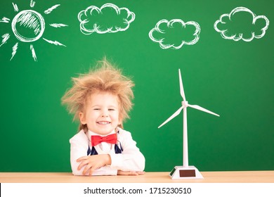 Bright Idea! Funny Child Student With Wind Turbine. Happy Kid Against Green Chalkboard. Alternative Wind Energy Concept. Back To School