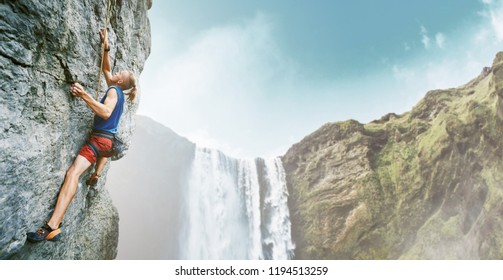 bright image of young man rock climber with long hair wearing in bright red shorts and blue t-shirt climbing the challenging route on the cliff. rock climber climbing on a limestone wall on the