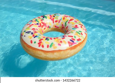 Bright Inflatable Doughnut Ring Floating In Swimming Pool On Sunny Day