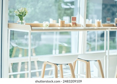 The bright interior of the cafe with a table. Against the background of panoramic windows, a dining area with chairs in a row. A meeting area in a minimalist restaurant. High quality photo - Powered by Shutterstock