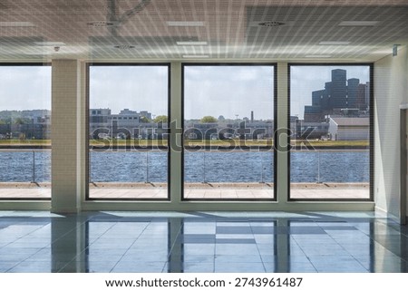 A bright interior with large floor to ceiling windows overlooking the Royal Albert Dock in east London, UK