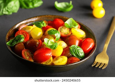 Bright juicy salad with colorful cherry tomatoes and aromatic basil leaves on black stone table close up. Healthy vegan food concept. - Powered by Shutterstock