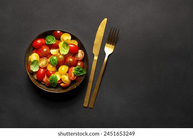 Bright juicy salad with colorful cherry tomatoes and aromatic basil leaves on black stone table top view. Healthy vegan food concept.

 - Powered by Shutterstock