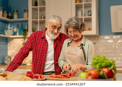 in a bright kitchen an elderly woman in a light green shirt with her husband are preparing healthy dinner cutting vegetables - Powered by Shutterstock