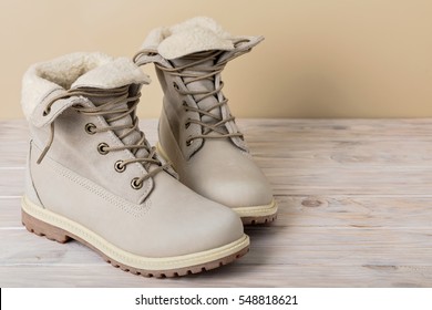 Bright leather winter boots on a light wooden background. - Shutterstock ID 548818621