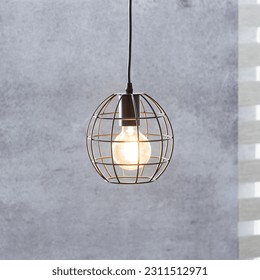 A bright light bulb illuminates a metal, caged ceiling fixture - Shutterstock ID 2311512971