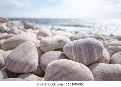 Bright light on the island stone beach with beautiful pebbles shaped by the ocean waves