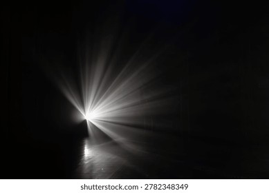 Bright light source projects rays into a dark environment, illuminating a reflective floor with dramatic shadows and highlights