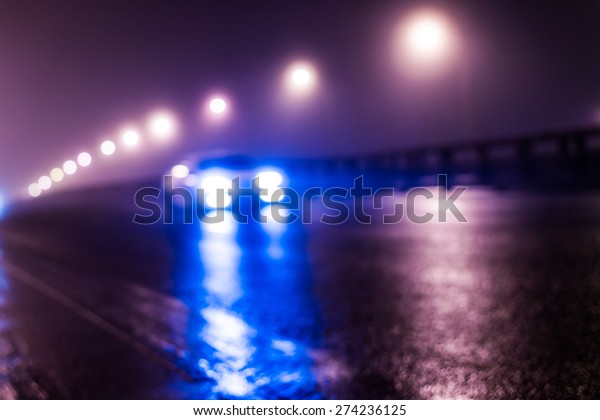 The bright lights\
of the city at night, the car racing on the road bridge. Defocused\
image, in blue tones