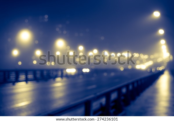 The bright lights of the city at night, the cars
goes over the road bridge. Defocused image, image in the
yellow-blue toning