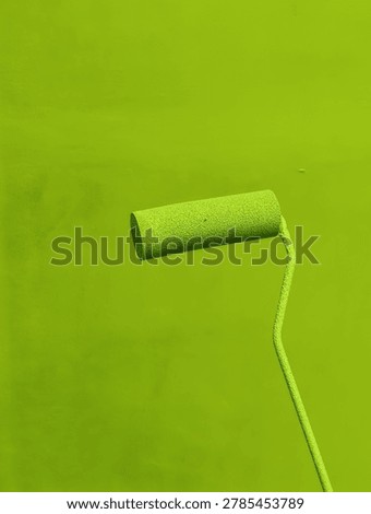 Bright lime paint roller with handle visible against a uniform lime background, close up texture and subtle shadows.