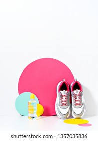Bright Lit Scene With Bottle Of Water, Chunky Sneakers And Huge Confetti. Colorful Casual Wear Or Footwear. 