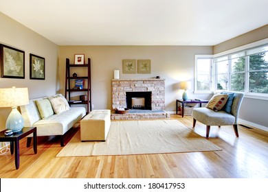 Bright Living Room With A Hardwood Floor And Rocky Background Fireplace. Furnished With Classic Sofa And Chair, Table And Bookshelf