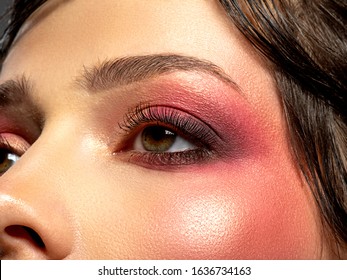 Bright makeup on a woman's eye. Bright red eye makeup. Macro shot of a woman's eye with cherry-colored blush. Colorful and vivid makeup. Fashionable eye make-up. Art. Trendy style. 