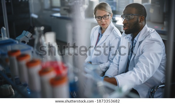 Bright\
Medical Science Laboratory with Diverse Team of Research Scientists\
Working. Young Female Microbiologist Talks to a Male Biochemist\
about New Test Results. High-Tech\
Equipment.