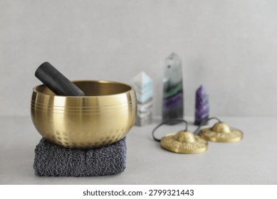 A bright, minimal wellness composition featuring a singing bowl surrounded by folded towels, tingsha bells, and healing crystals including amethyst, fluorite, and aragonite. 