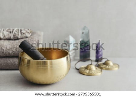 A bright, minimal wellness composition featuring a singing bowl surrounded by folded towels, tingsha bells, and healing crystals including amethyst, fluorite, and aragonite. 
