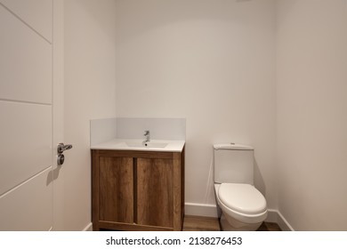 Bright Modern Powder Room With White Walls And Sink Unit With Wooden Doors, Toilet And Sink In Brand New Show Home