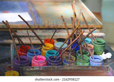 
Bright multi colored jars with paint and brushes in them