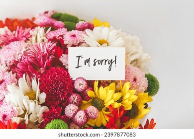 bright multi-colored bouquet of flowers with white card with the inscription i am sorry, the concept of apologies.