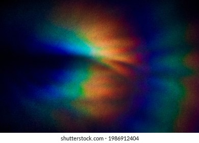 Bright multicolored glare on dark rough textured cardboard. Soft rainbow light. Abstract colorful background.