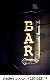 Bright neon arrow and sign bar on the wall. Realistic luminous design element. Night life. Copy space